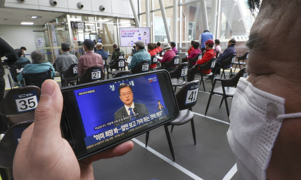 지난 10일 서울의 코로나19 백신접종센터에서 한 시민이 휴대전화로 문재인 대통령 취임 4주년 특별연설을 시청하고 있다. 연합뉴스