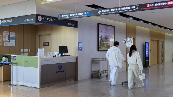 환자와 보호자가 병원 로비를 지나고 있다.