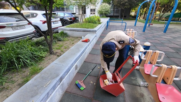 아파트 경비근로자 김 씨가 전날 누군가 공원에 버리고 간 과자봉투와 음료병을 정리하고 있다.