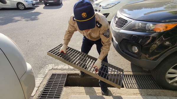 아파트 경비근로자 김 씨가 침수방지를 위한 빗물받이 뚜껑을 들어올리고 있다. 빗물받이 뚜껑은 성인 남성이 간신히 들어올릴 수 있는 무게였다.