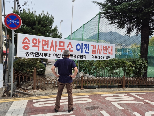 ▲ 한 주민이 송악면 행정복지센터 이전 반대 현수막을 바라보고 있다.